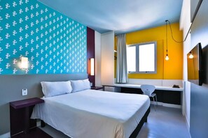 Una habitación de hotel moderna con una cama, un escritorio y una silla.