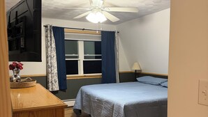 A bedroom with a bed, a desk, a ceiling fan, and a window with curtains. - Waterfront lake house retreat located in Baileyville Maine! (Baileyville)