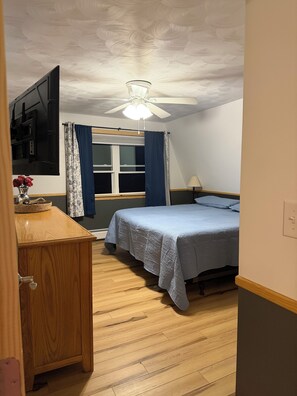 A bedroom with a bed, a desk, a ceiling fan, and a window with curtains. - Waterfront lake house retreat located in Baileyville Maine! (Baileyville)