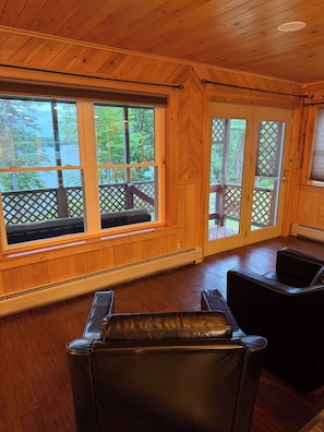 A wooden-paneled room with a large window, a bench, and two leather chairs.