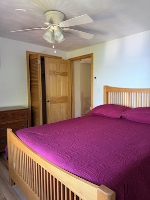 A bedroom with a wooden bed, a ceiling fan, and a wooden wardrobe.
