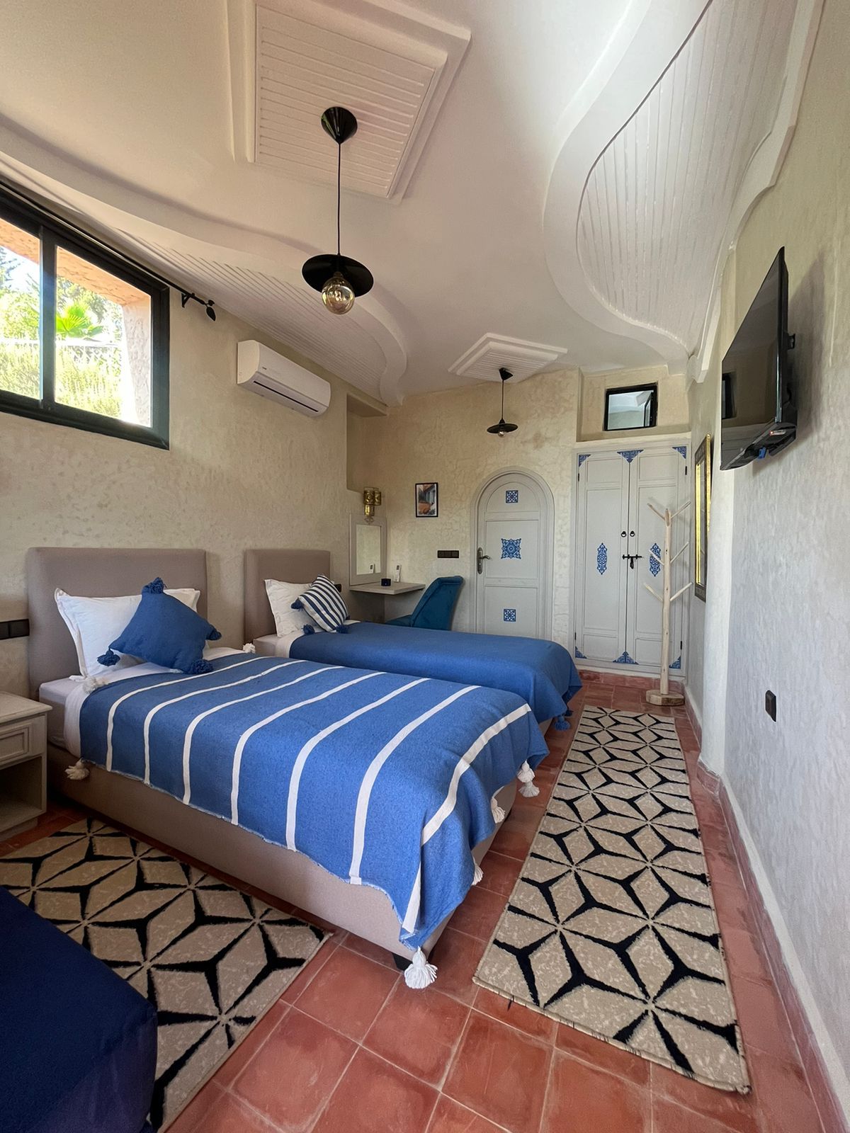 A hotel room with two beds, a TV mounted on the wall, and a patterned floor.