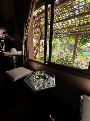Una habitación con vistas a un jardín a través de una ventana con una celosía de madera.