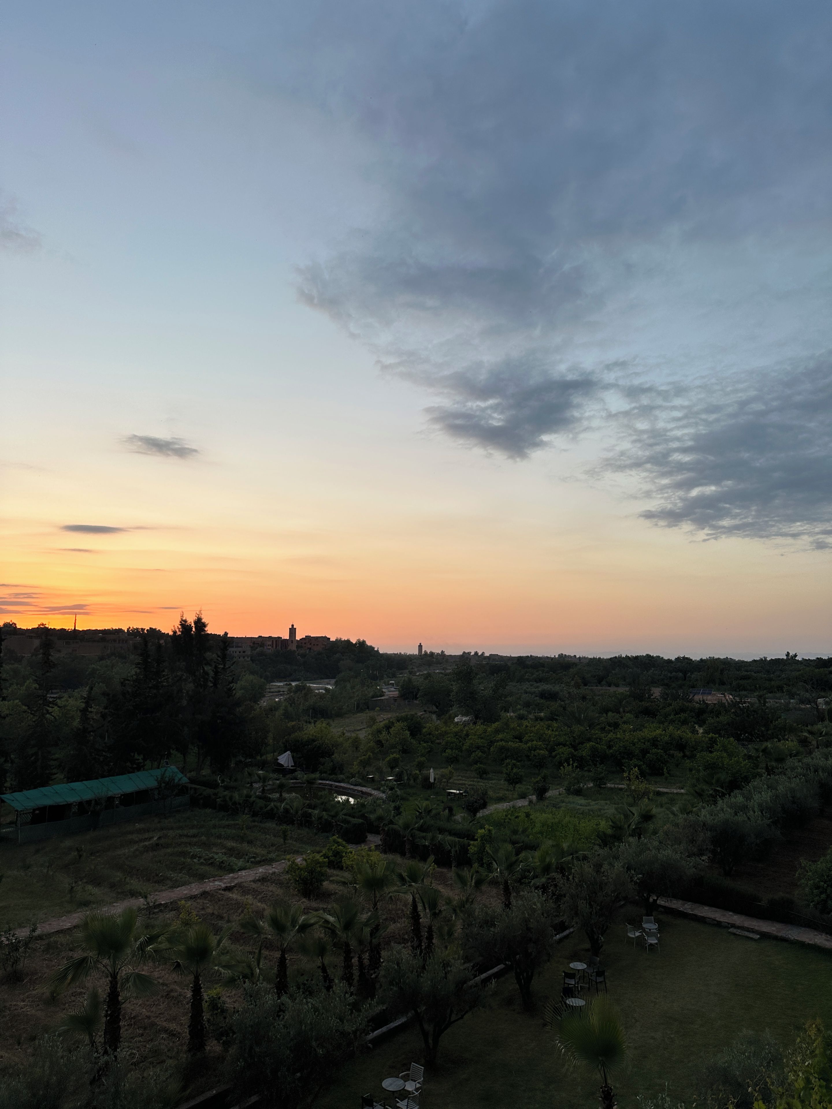 A landscape with a sunset, trees, and a distant building.