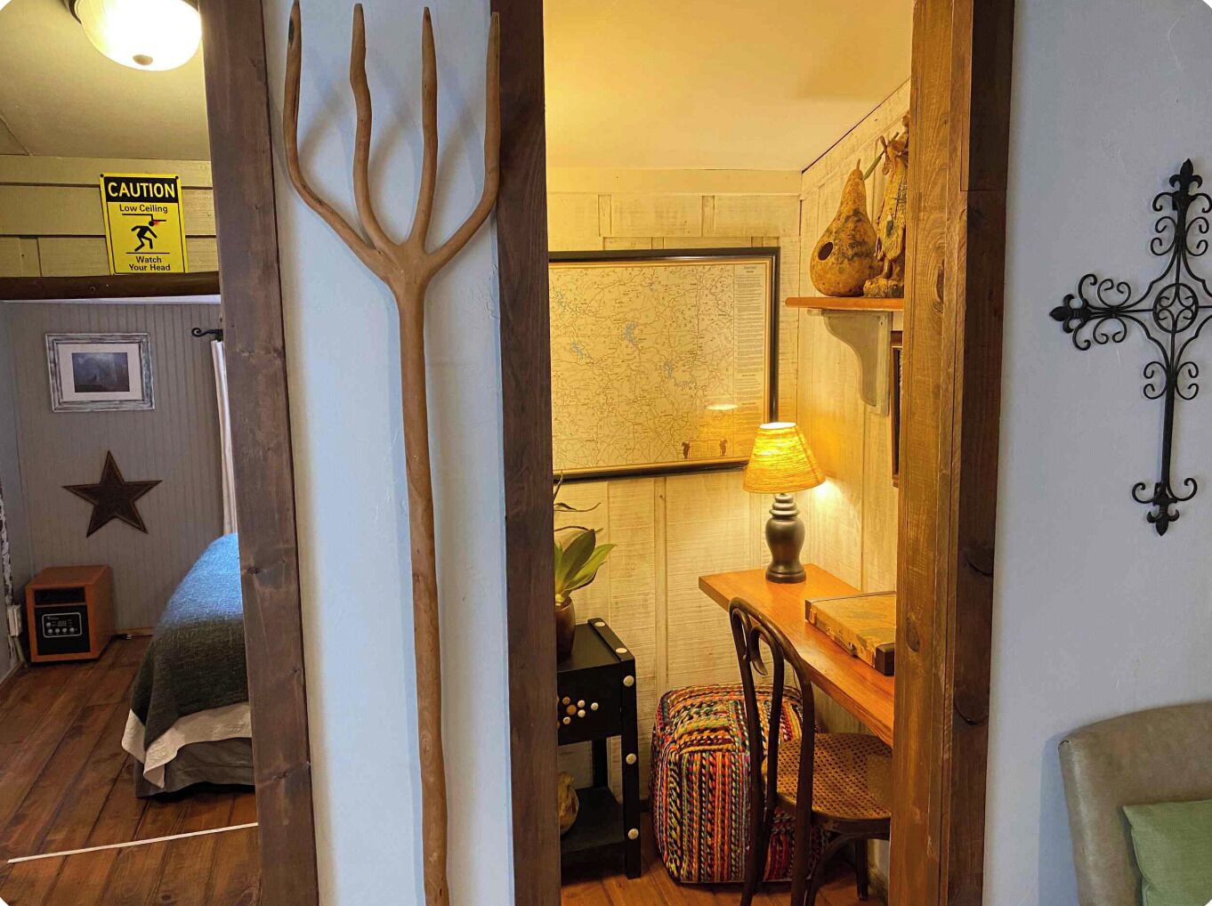 A room with a low ceiling warning sign, a map on the wall, a lamp on a table, and a star decoration on the wall.