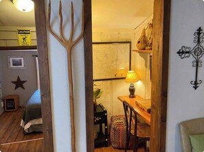 Una habitación con un cartel de advertencia sobre techo bajo, un mapa en la pared, una lámpara sobre una mesa y una decoración con forma de estrella en la pared.