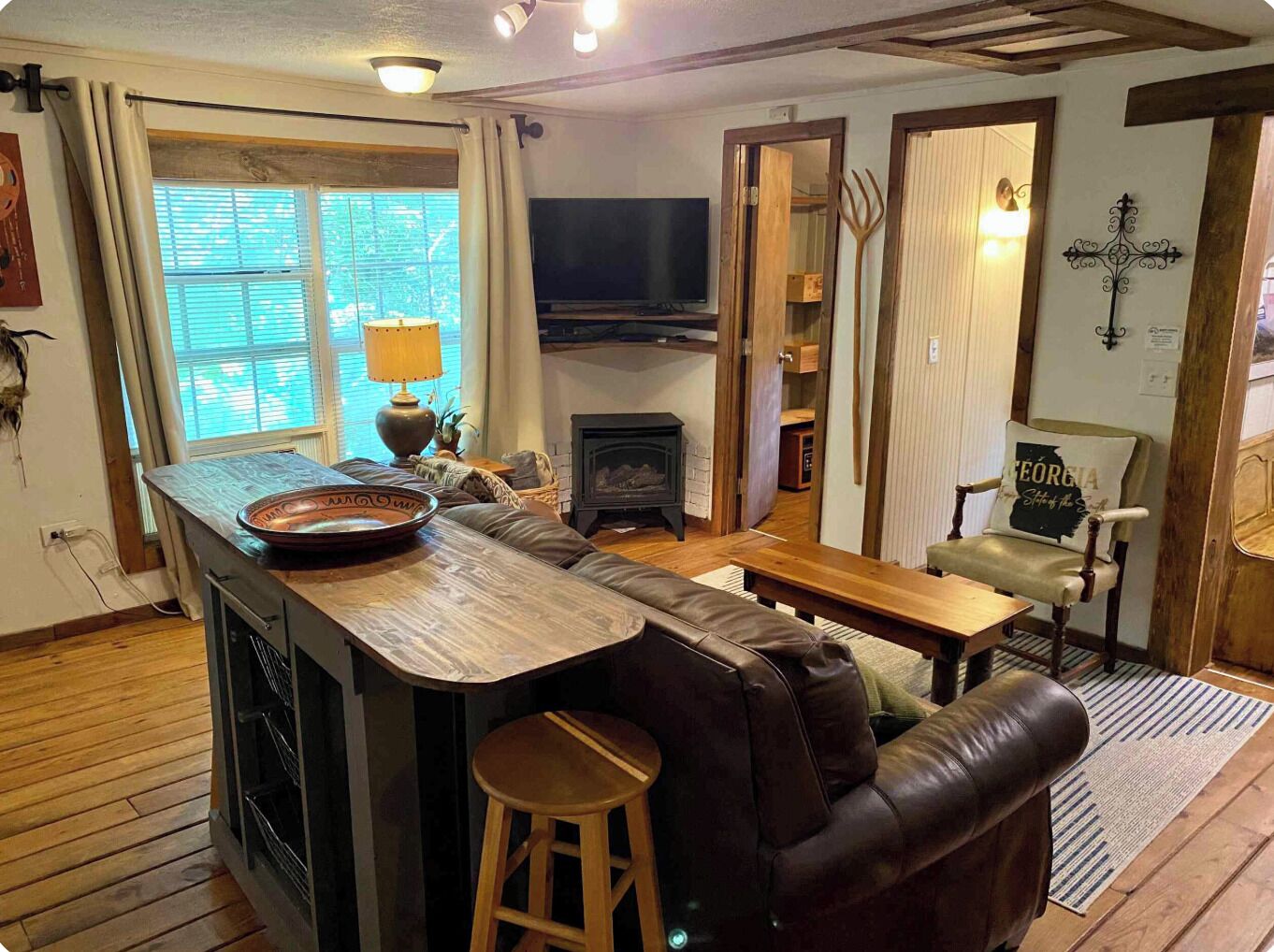 A cozy living room with a wooden coffee table, a leather sofa, a television, and a fireplace.