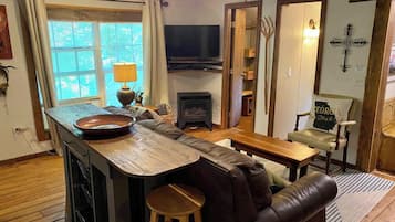 A cozy living room with a wooden coffee table, a leather sofa, a television, and a fireplace.