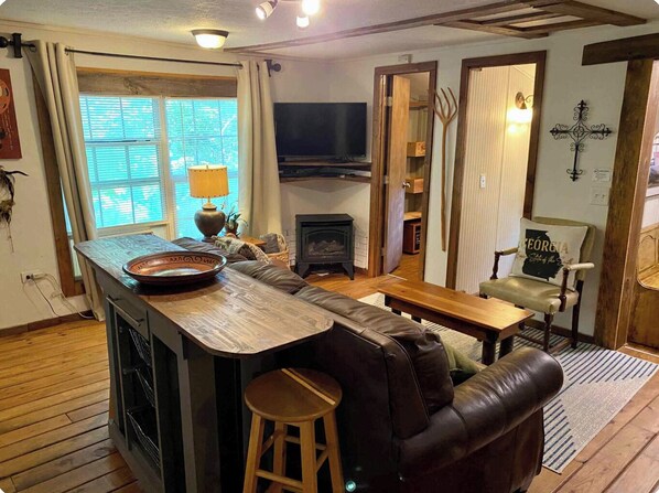 A cozy living room with a wooden coffee table, a leather sofa, a television, and a fireplace.