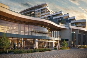 A modern building with a glass facade, outdoor seating area, and a sign reading 'BOARDWALK BISTRO'. - 909 Aqua 1 Resort Condo | Panoramic Okanagan Views (Kelowna)