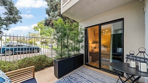 Ein Balkon mit einer Sitzgelegenheit, einem Tisch und Blick auf die Straße.