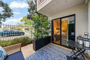 A balcony with a seating area, a table, and a view of the street. - Steps to Sail Bay · Full 2026 Remodel · Garage Parking · Spa (San Diego)