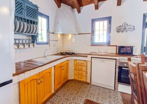 A kitchen with wooden cabinets, a built-in dishwasher, and a stove. - Zambra: 3-Bedroom Villa with Private Pool in Frigiliana (Frigiliana)