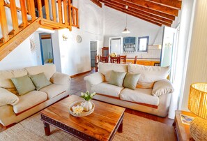 A spacious living area with two sofas, a coffee table, and a kitchen in the background. - Zambra: 3-Bedroom Villa with Private Pool in Frigiliana (Frigiliana)