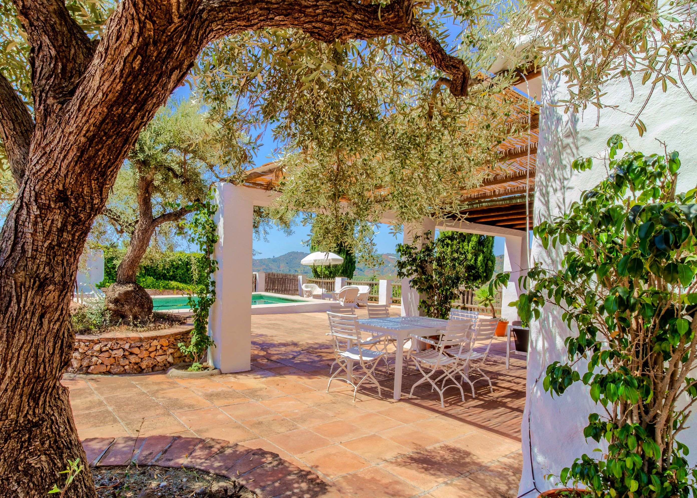 Un patio con piscina, mobiliario exterior y vistas al paisaje.