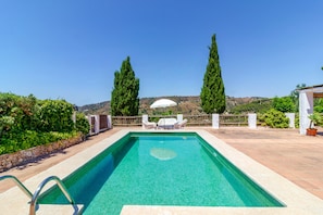 A rectangular swimming pool with clear blue water, surrounded by a stone deck. There are white lounge chairs and a white umbrella on the deck. - Zambra: 3-Bedroom Villa with Private Pool in Frigiliana (Frigiliana)