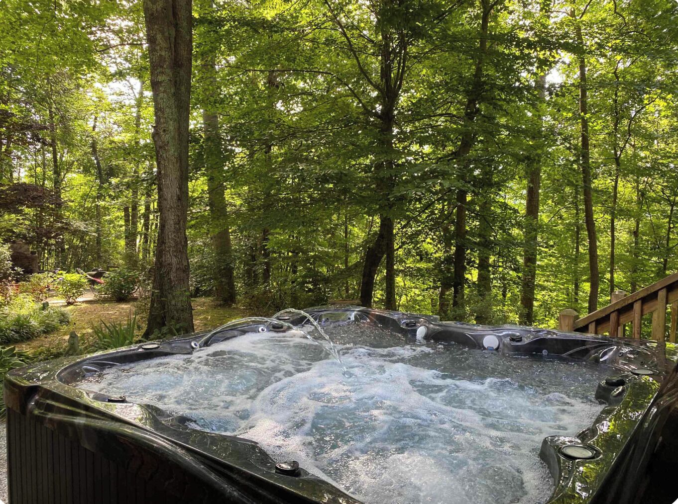 A hot tub in a forested area with a wooden deck.