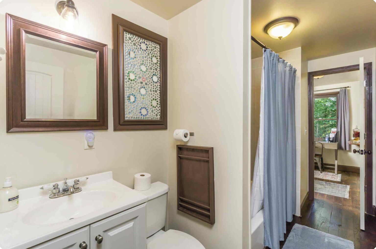 A bathroom with a sink, mirror, toilet, and shower curtain.
