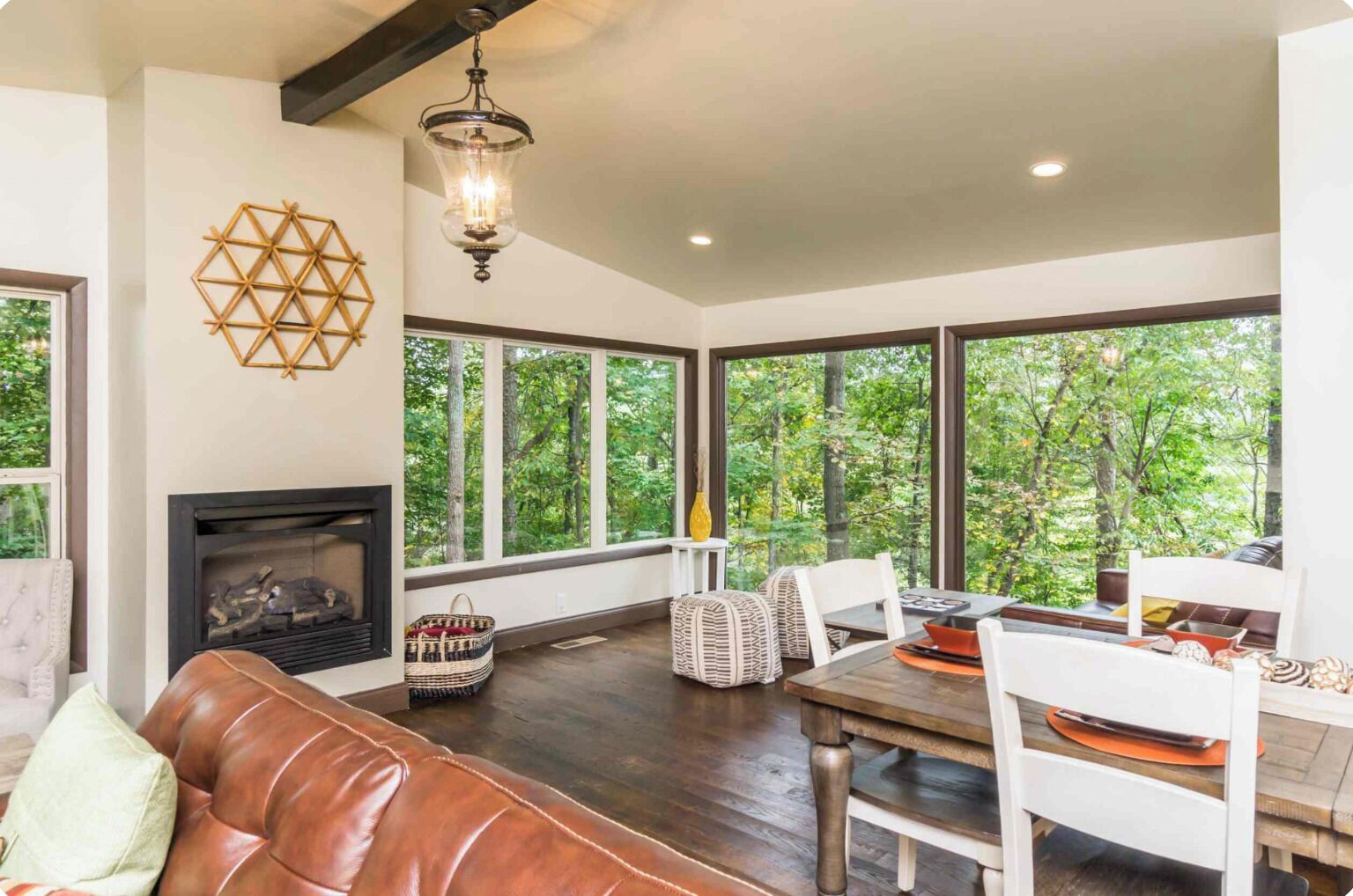 A spacious room with a fireplace, large windows, a dining table, and a leather couch.