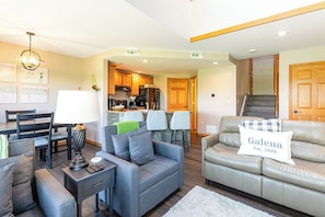 A modern living room with a sofa, a coffee table, and a dining area with chairs and a table. - Perfect Fall Getaway: charming 1-bedroom townhome in Galena on golf course (Galena)