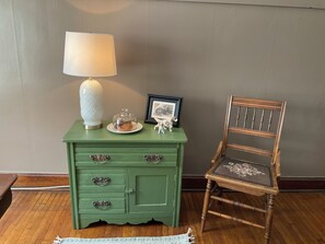 A green wooden dresser with a lamp, a plate with a pastry, and a framed picture.