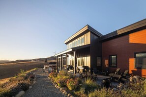 Ein modernes Haus mit einer Terrasse, Sitzgelegenheiten im Freien und Blick auf die umliegende Landschaft.