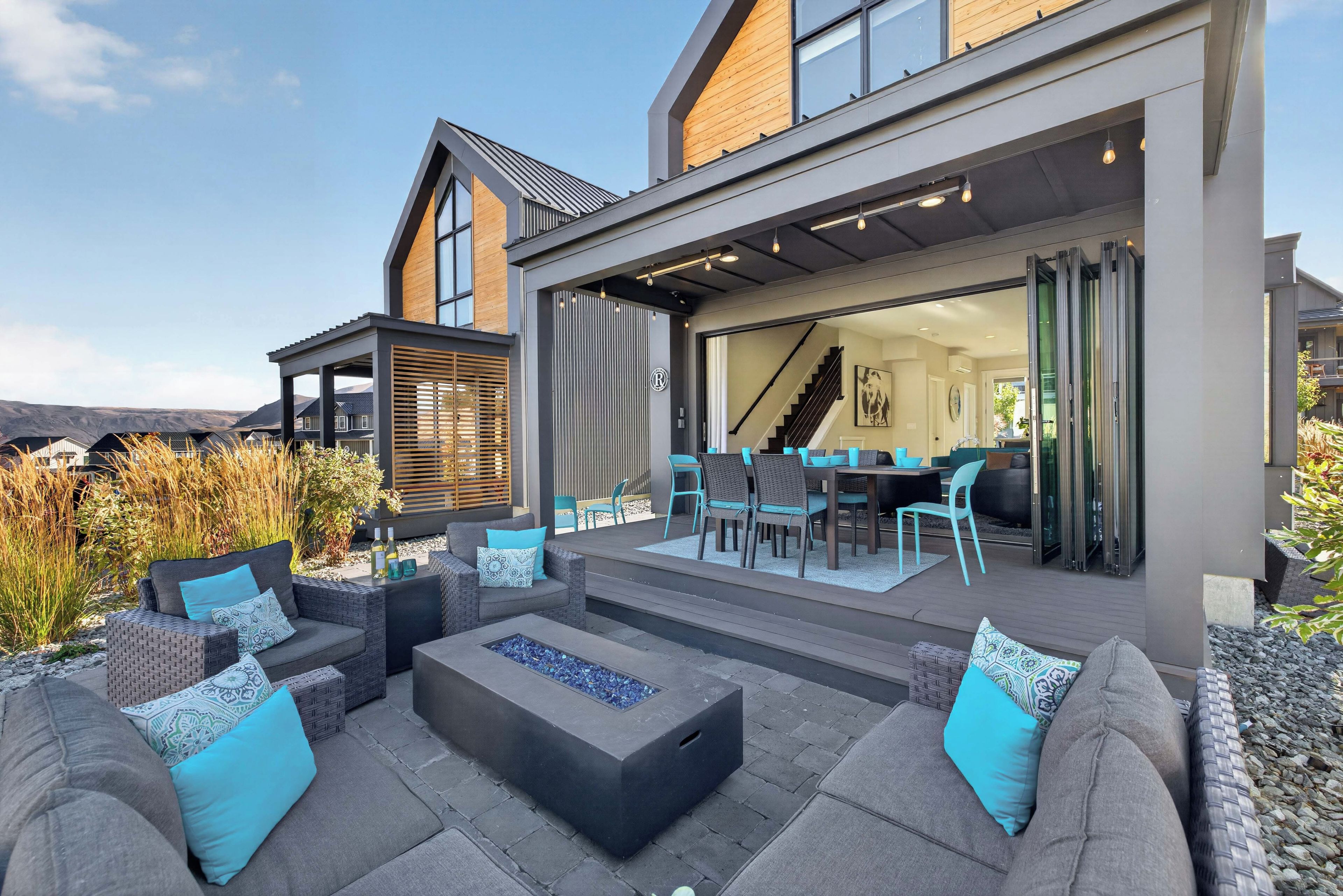 A modern outdoor patio with a fire feature, seating, and a view of the interior.