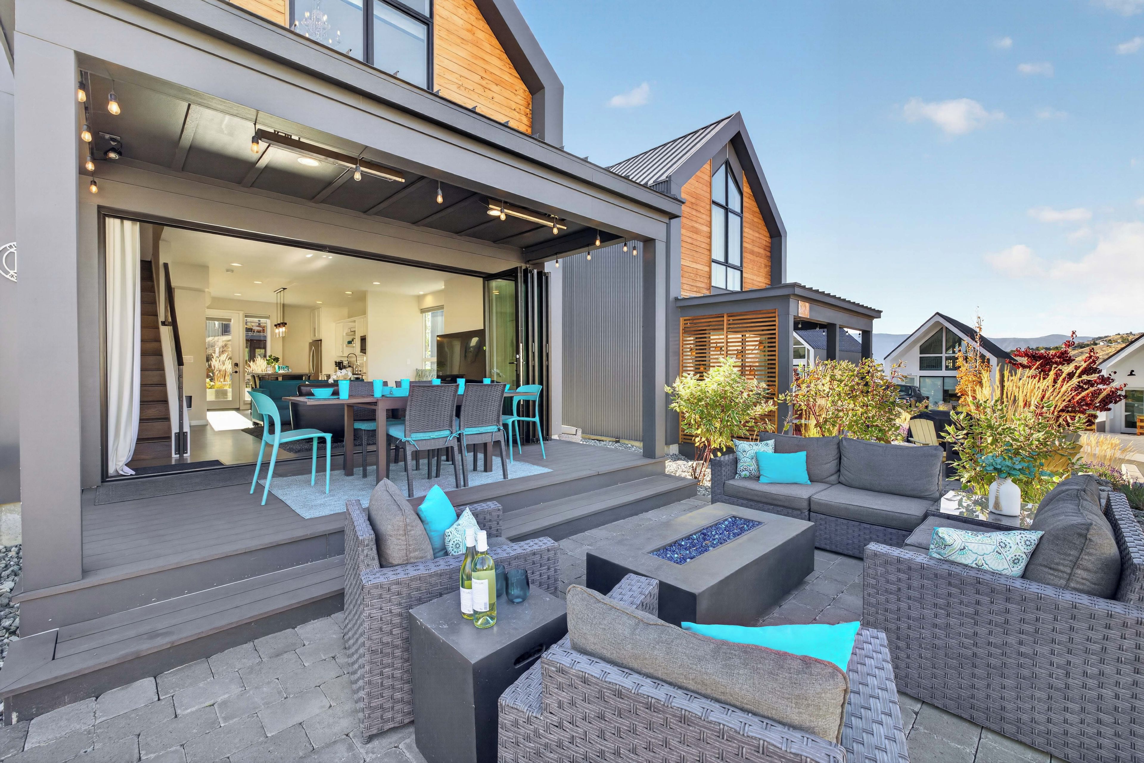 A modern outdoor patio with wicker furniture, a dining area, and a view of the surrounding neighborhood.