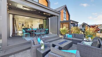 A modern outdoor patio with wicker furniture, a dining area, and a view of the surrounding neighborhood.