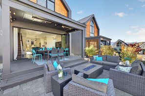 Une terrasse extérieure moderne, aménagée avec des meubles en osier, un coin repas et offrant une vue sur le quartier environnant.