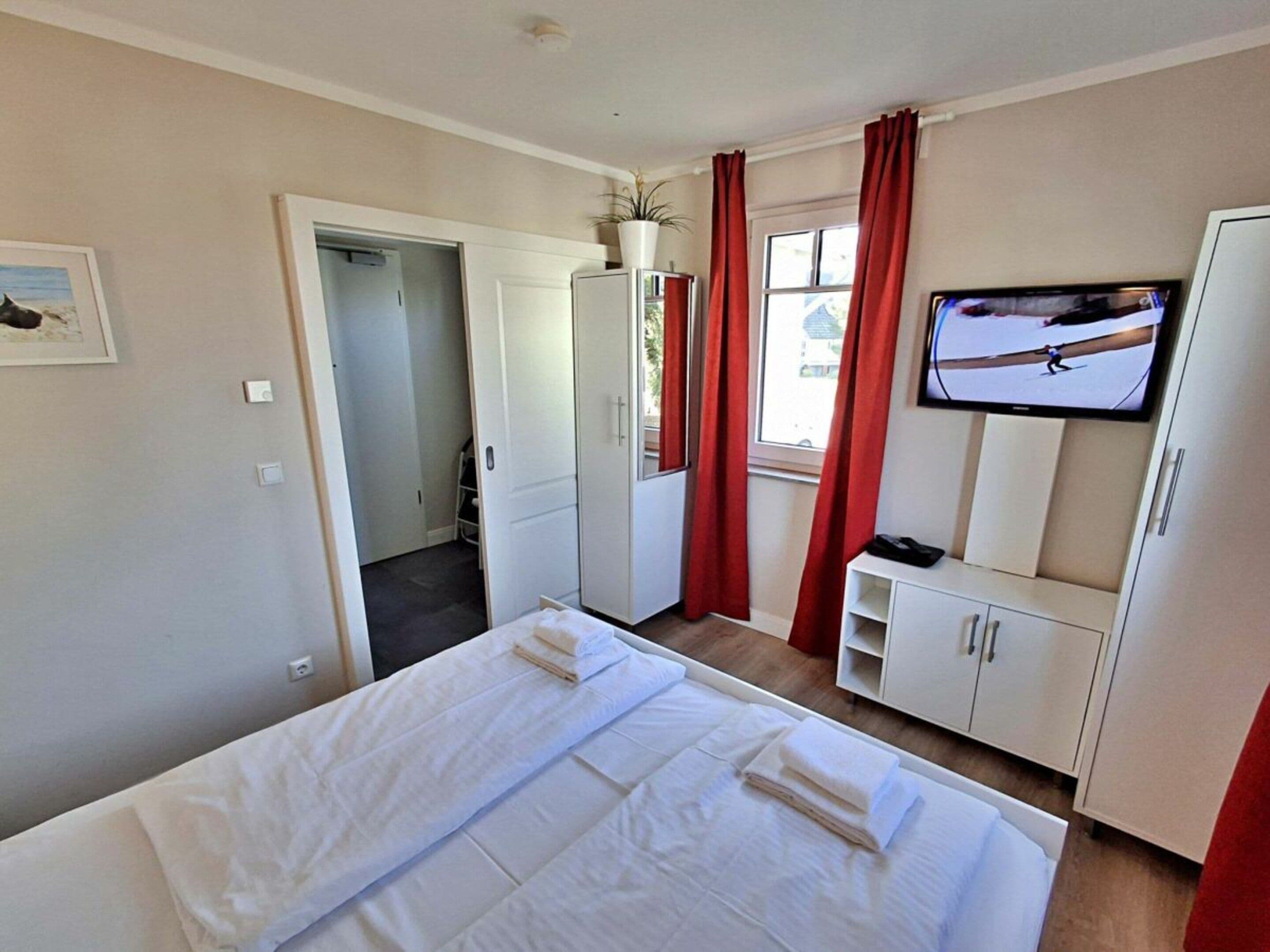 A hotel room with a bed, a television, a wardrobe, and a door leading to a bathroom.