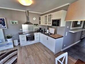 A modern kitchen with white cabinetry, a stainless steel range hood, and a built-in oven. - Holiday Apartment With 1 Bedroom (Heringsdorf)