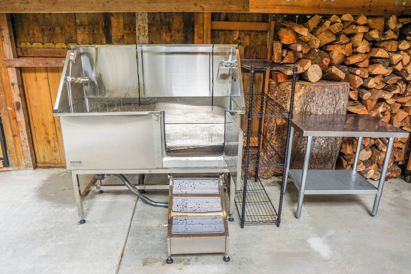 Cocina comercial con electrodomésticos de acero inoxidable, un lavaplatos de metal y una mesa de metal con una rejilla.