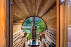 A wooden cabin with a circular window, a fireplace, and a bench.