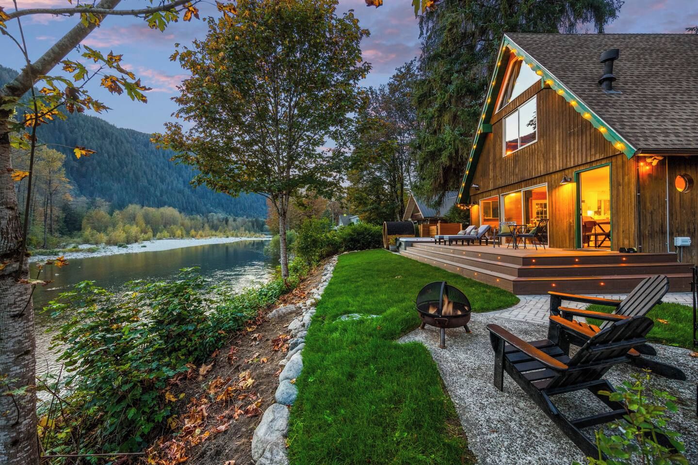 A lakeside cabin with a deck, a fire pit, and outdoor seating.