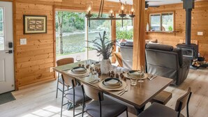 Ein gemütliches Blockhaus-Interieur mit Essbereich, Kamin und Blick ins Freie.