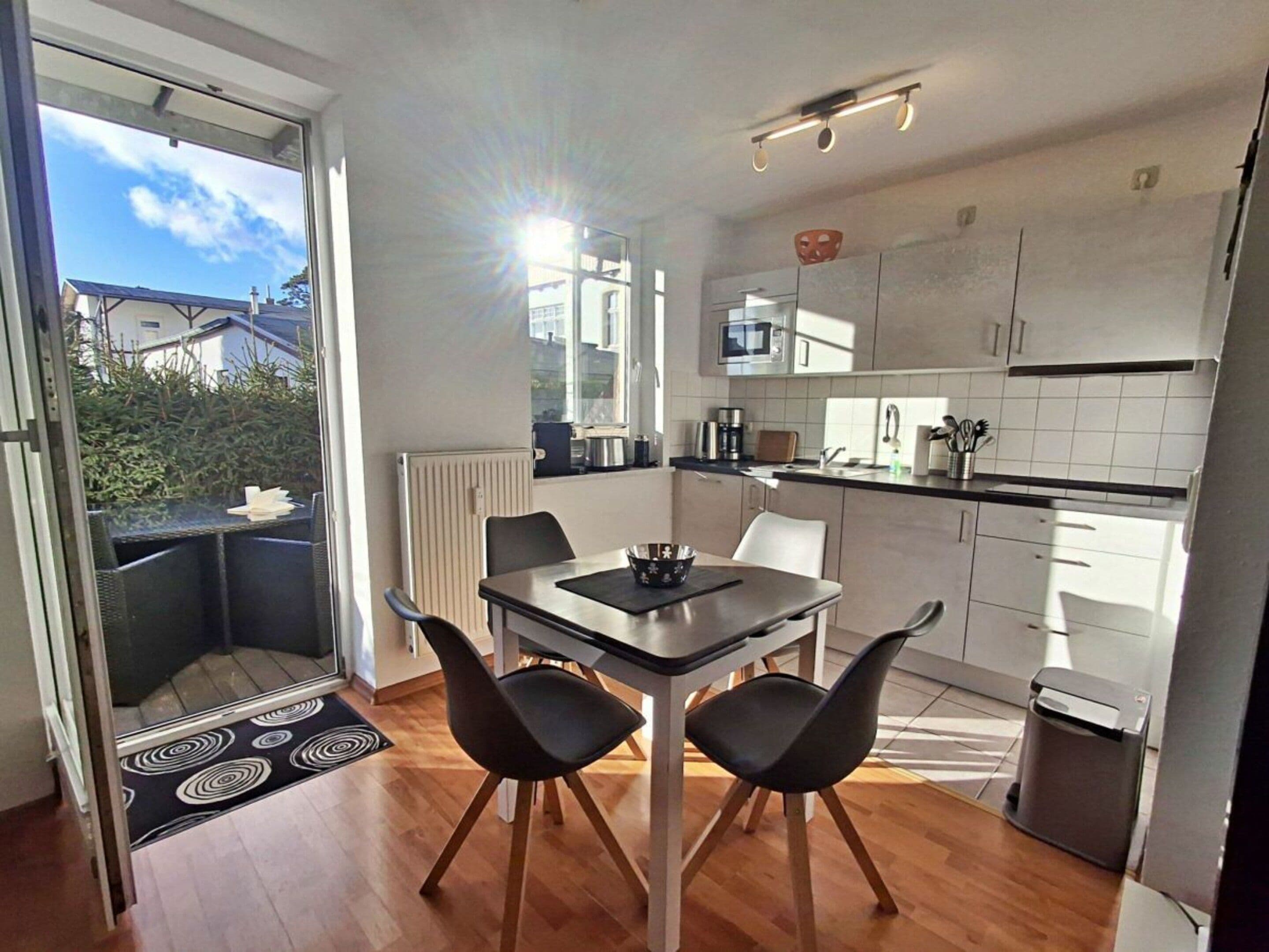 A modern kitchen with a dining area, featuring a table with chairs, a built-in oven, and a window providing natural light.