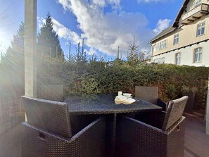 An outdoor dining area with wicker furniture and a table set for two. - Villa Waldstrasse 05 (Heringsdorf)