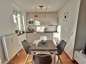 A compact kitchen with a dining table and chairs, a microwave, and a sink. - Villa Waldstrasse 05 (Heringsdorf)