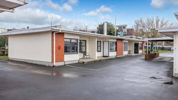 A single-story building with a flat roof, a covered parking area, and a small outdoor seating area.