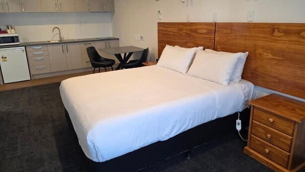 Une chambre d’hôtel comprenant un lit, une table de chevet et un coin cuisine.