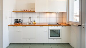 A compact kitchen with white cabinets, a stainless steel sink, a built-in oven, and a window providing natural light. - Family-friendly 3-bedroom Apartment for 6 Guests (Antwerp)