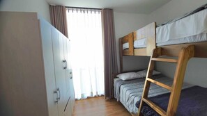 A room with bunk beds, a wardrobe, and a window with curtains.