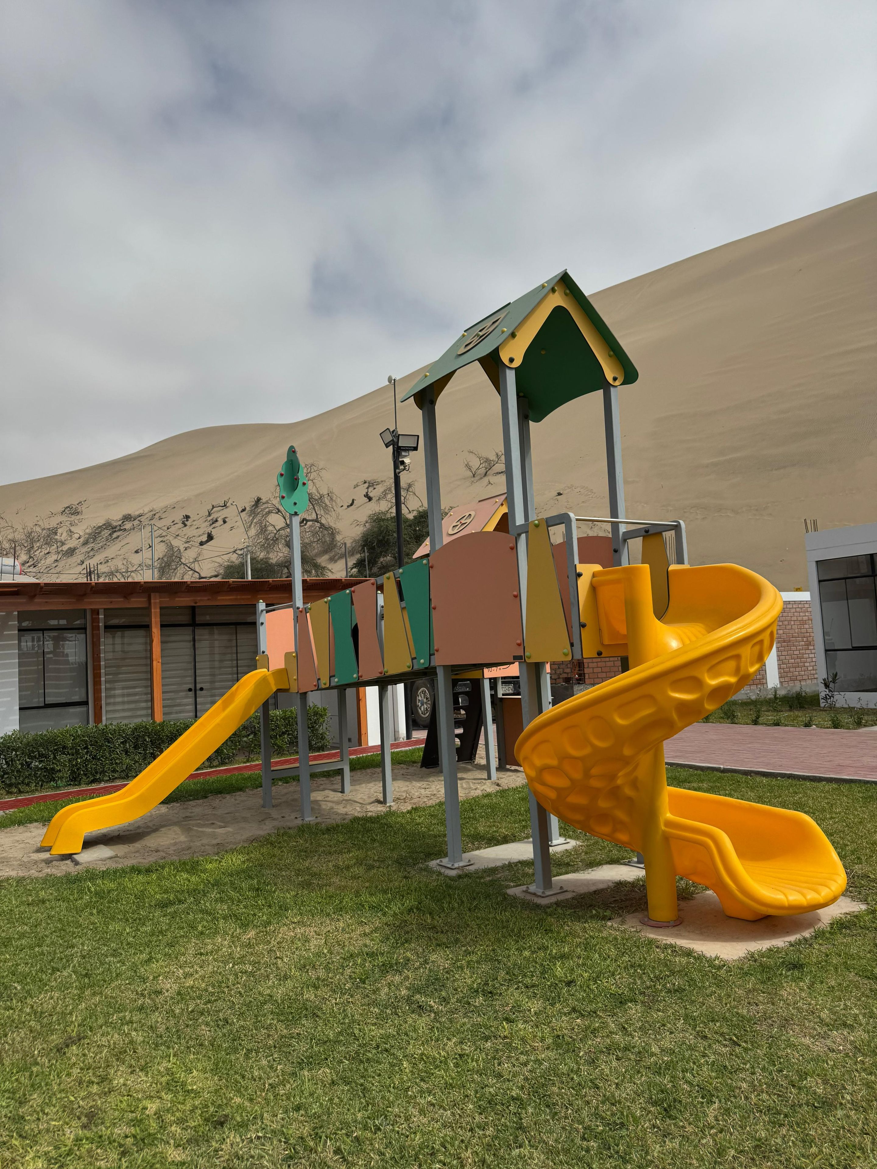 Ein Spielplatz mit einer gelben Rutsche und einer Kletterkonstruktion.