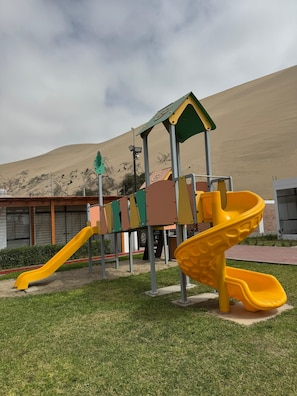 A playground with a yellow slide and a climbing structure.