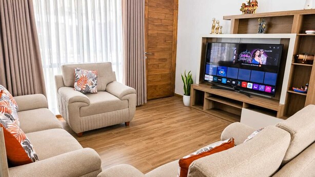 Ein modernes Wohnzimmer mit Flachbildfernseher, zwei Sofas, einem Couchtisch und einer Topfpflanze.