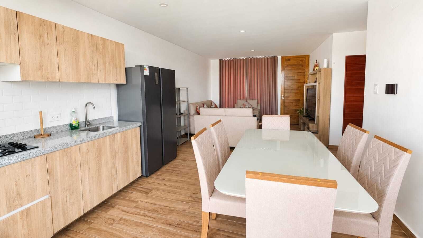 A modern kitchen with a central island, wooden cabinets, and a built-in refrigerator.
