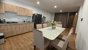 Eine moderne Küche mit Holzausstattung, einem eingebauten Backofen und einem Essbereich mit weißem Tisch und Stühlen.