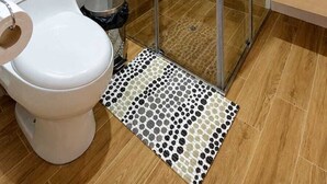 Ein modernes Badezimmer mit einer Duschkabine, einer Toilette, einem Waschbecken und einem Spiegel.