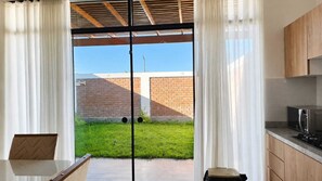 A modern kitchen with a built-in microwave and a sliding glass door leading to a grassy backyard.